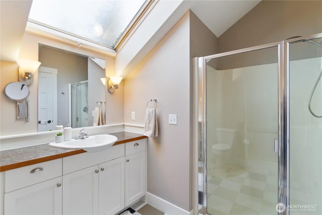 full bathroom featuring vaulted ceiling with skylight, a shower stall, vanity, and baseboards