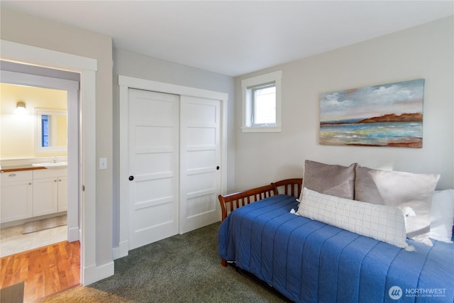 bedroom featuring a closet, baseboards, carpet, and a sink