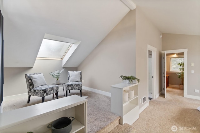 sitting room with visible vents, vaulted ceiling with skylight, baseboards, and carpet floors