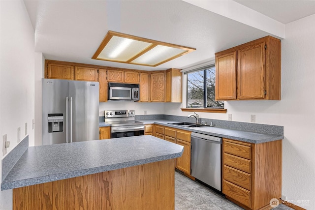 kitchen featuring a sink, stainless steel appliances, brown cabinets, and a peninsula