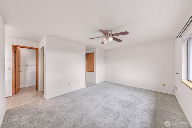 unfurnished room featuring baseboards, light carpet, and ceiling fan