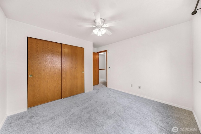 unfurnished bedroom with a closet, ceiling fan, baseboards, and carpet