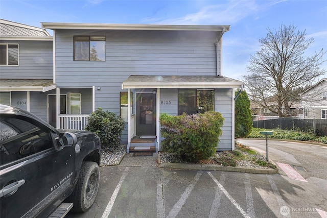 view of property with a standing seam roof, metal roof, fence, and uncovered parking