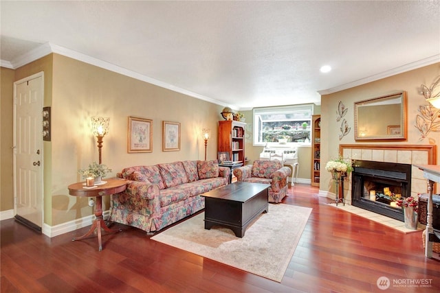 living room featuring crown molding, a fireplace, baseboards, and wood finished floors