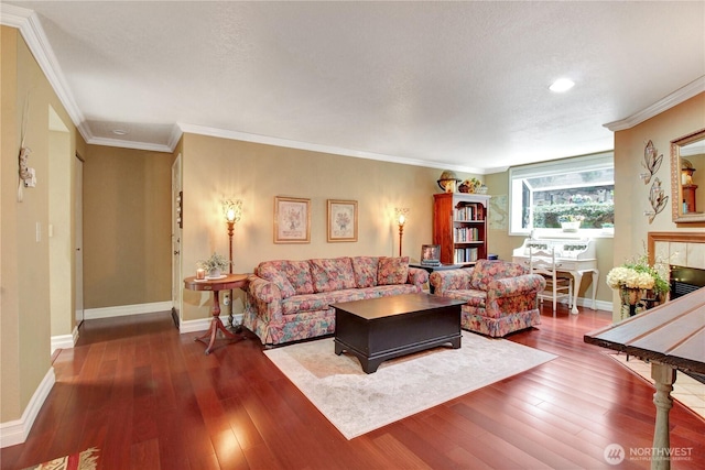 living area with a tile fireplace, crown molding, baseboards, and hardwood / wood-style flooring