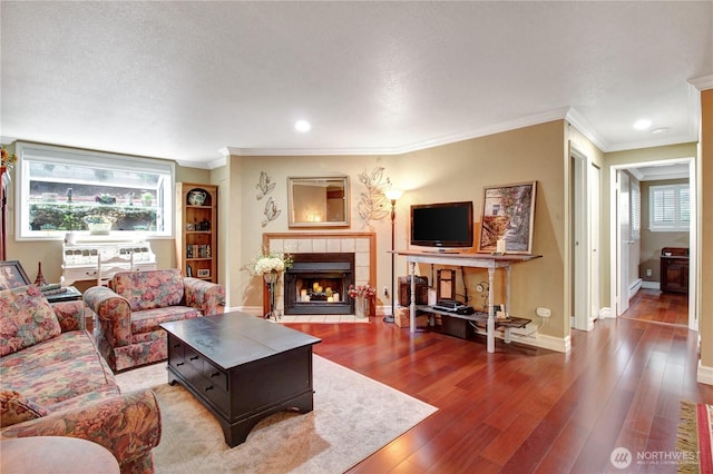 living area featuring hardwood / wood-style floors, plenty of natural light, baseboards, and a tiled fireplace