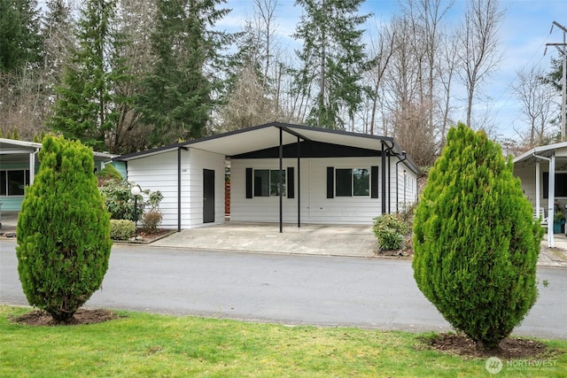 view of front of property featuring an attached carport, a front yard, and driveway