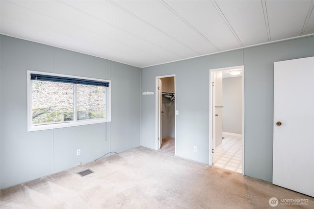 unfurnished bedroom featuring visible vents, carpet floors, connected bathroom, and a spacious closet