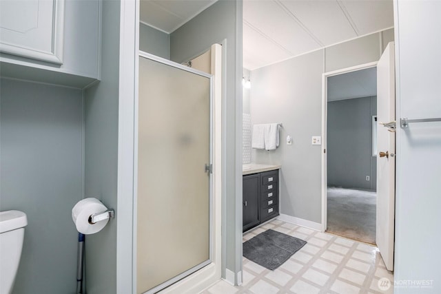 bathroom featuring tile patterned floors, toilet, a shower stall, baseboards, and vanity