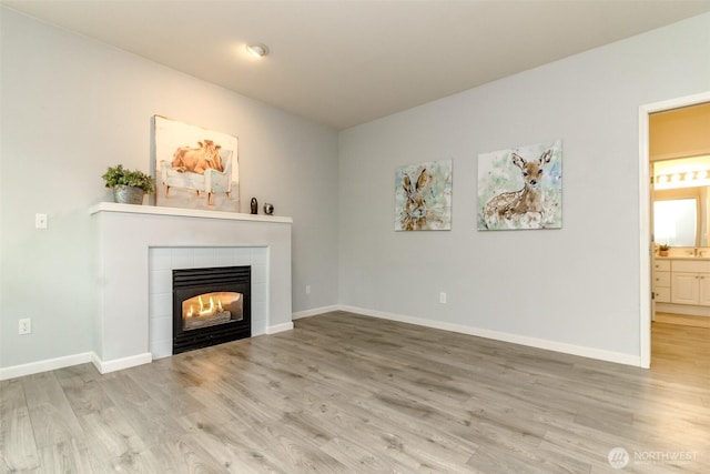 unfurnished living room with wood finished floors, a fireplace, and baseboards