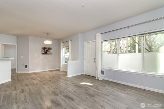 unfurnished living room featuring light wood finished floors, visible vents, and baseboards