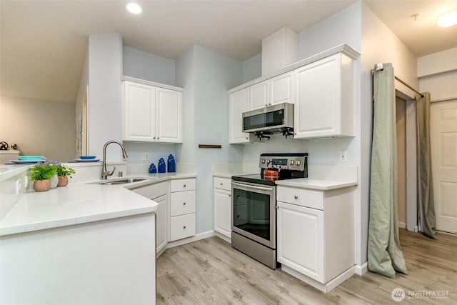 kitchen featuring a sink, stainless steel appliances, light wood-style flooring, and white cabinets