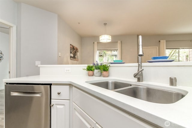 kitchen with pendant lighting, dishwasher, light countertops, white cabinetry, and a sink