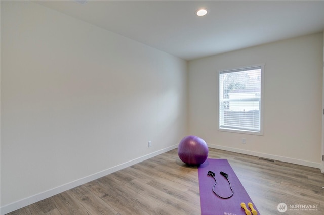 workout room featuring light wood finished floors, visible vents, and baseboards