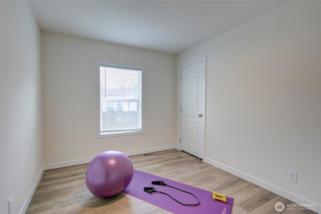 exercise area with visible vents, baseboards, and wood finished floors