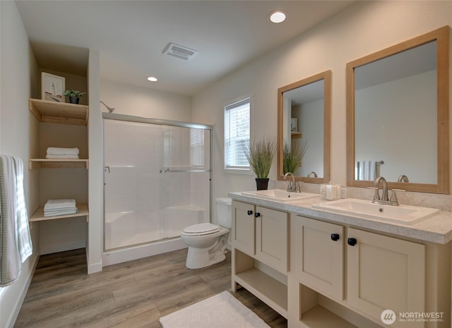 bathroom featuring wood finished floors, a sink, toilet, and a shower stall