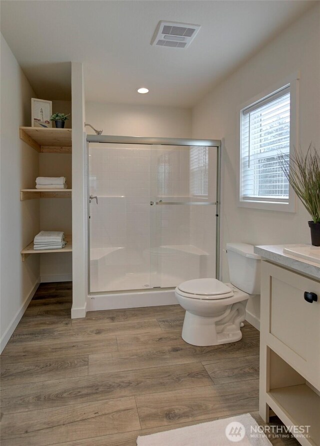 bathroom featuring toilet, a stall shower, visible vents, and wood finished floors