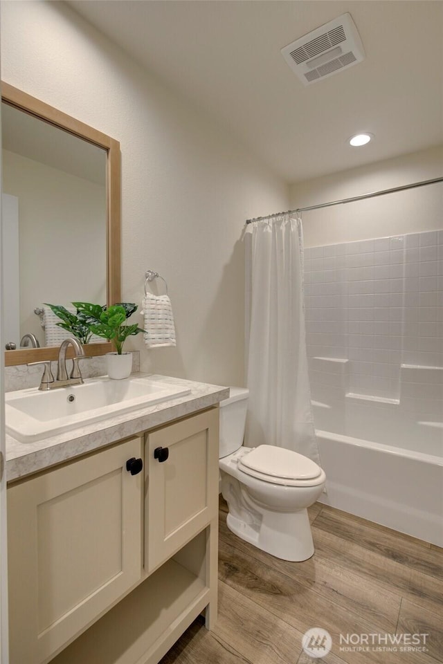 bathroom featuring visible vents, shower / bathtub combination with curtain, toilet, vanity, and wood finished floors