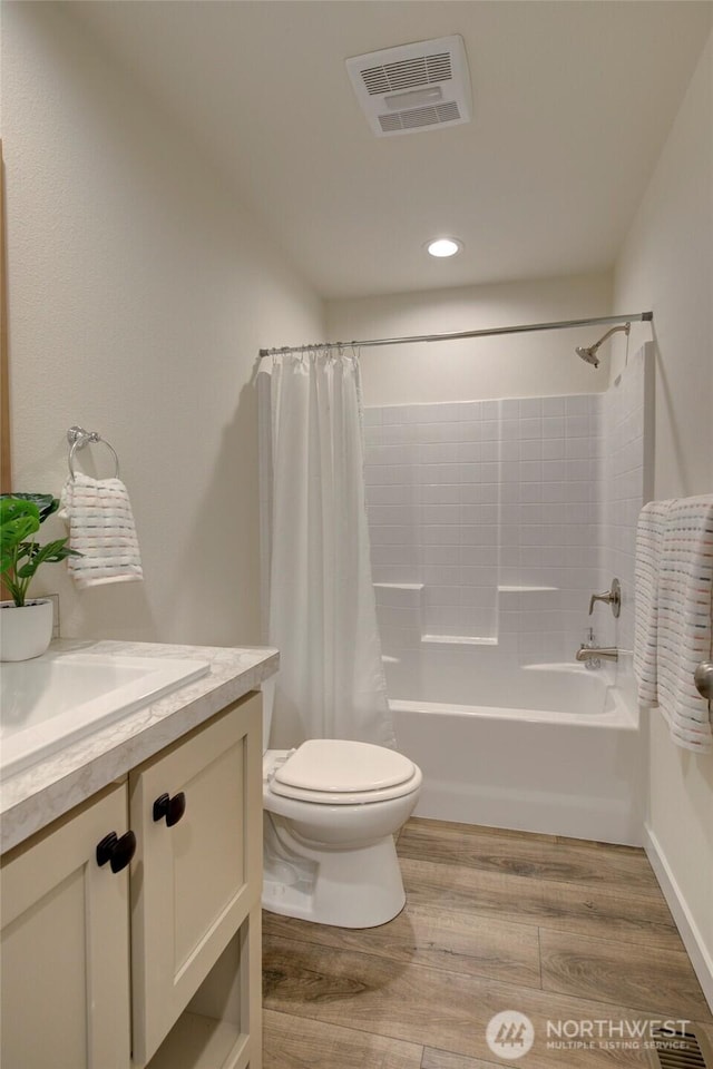 bathroom featuring toilet, wood finished floors, vanity, visible vents, and shower / bath combo