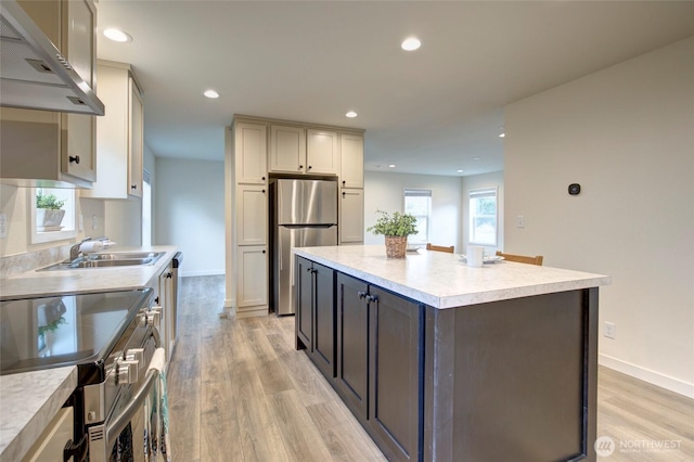 kitchen featuring recessed lighting, light wood-style flooring, appliances with stainless steel finishes, a sink, and extractor fan