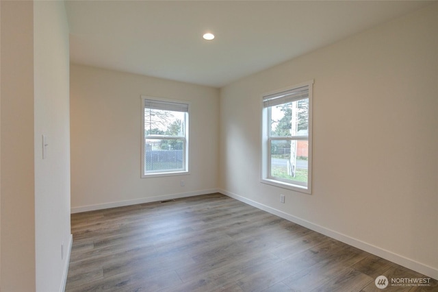 empty room with baseboards, wood finished floors, and a healthy amount of sunlight