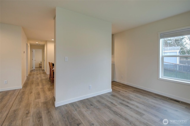 unfurnished room featuring wood finished floors, visible vents, and baseboards