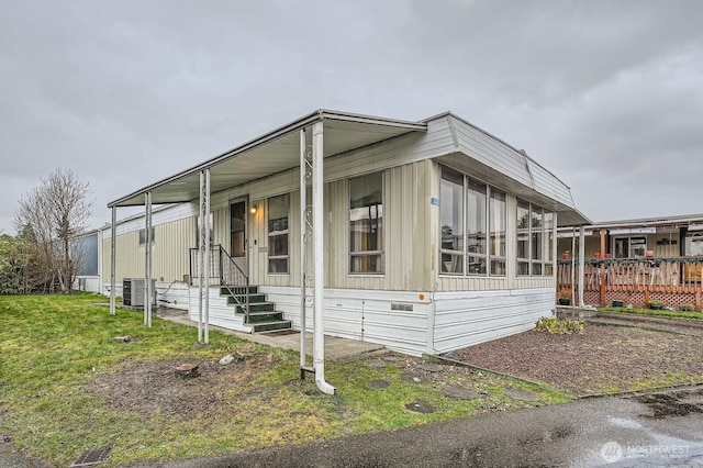 view of side of property with central air condition unit, a sunroom, and a yard