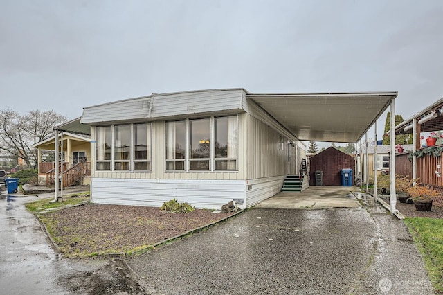 manufactured / mobile home with driveway, a carport, and entry steps