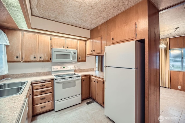 3222 S 183rd St, Seatac, WA 98188 - kitchen featuring white appliances, wood walls, a sink, visible vents, and light countertops