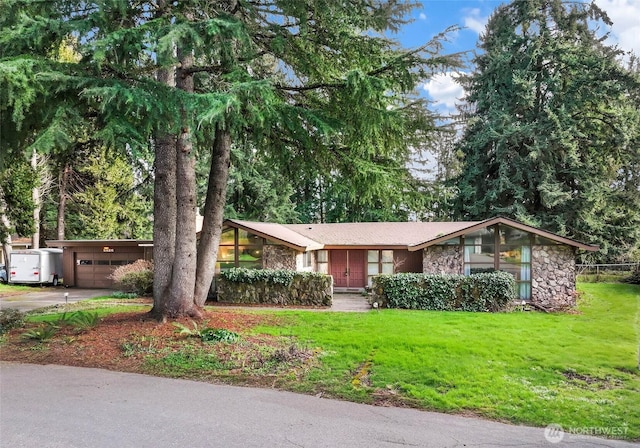 mid-century inspired home featuring driveway, stone siding, an attached garage, and a front yard