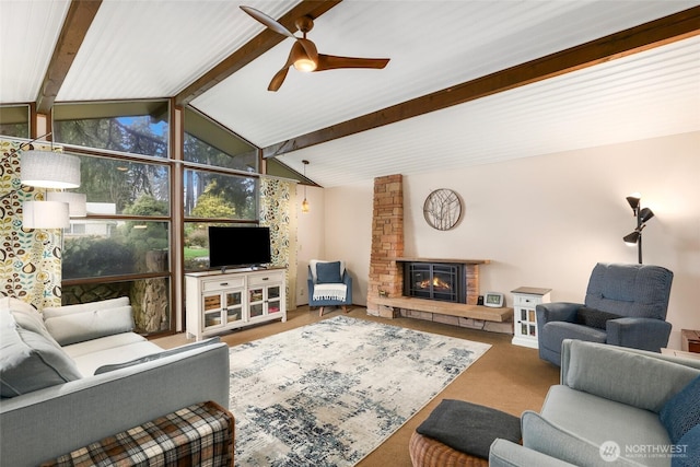 living room featuring lofted ceiling with beams, a fireplace, carpet flooring, and a ceiling fan