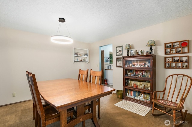 dining area with a textured ceiling, carpet flooring, and baseboards