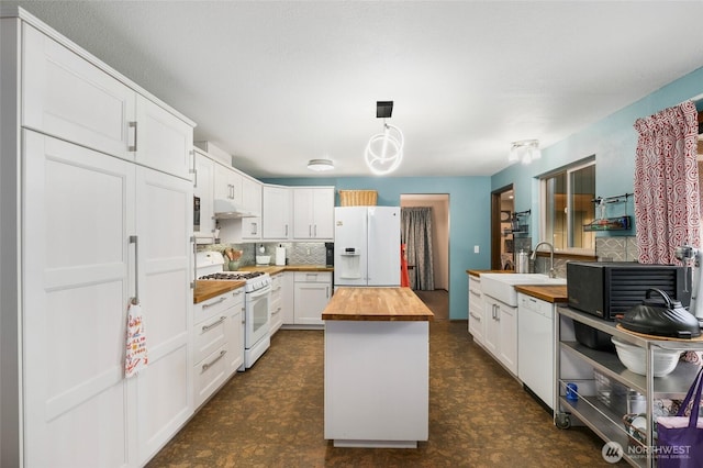 kitchen featuring under cabinet range hood, butcher block counters, white appliances, a sink, and tasteful backsplash