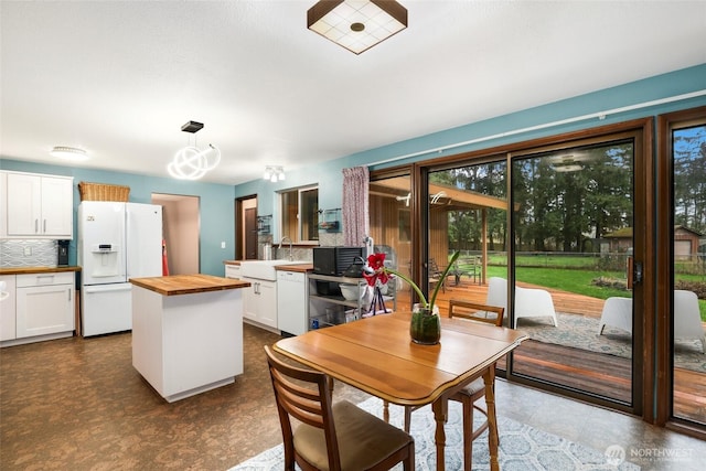 kitchen featuring a center island, tasteful backsplash, white cabinets, butcher block countertops, and white appliances