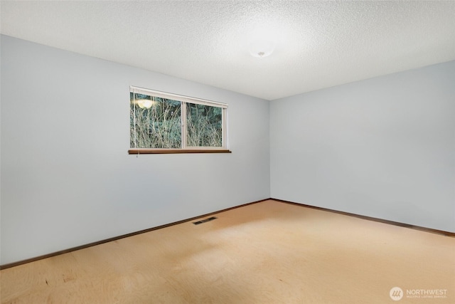 carpeted empty room with a textured ceiling, visible vents, and baseboards