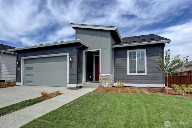 view of front of property with a front yard, concrete driveway, fence, and an attached garage