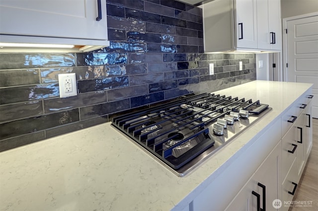20907 150th St E Unit 1460, Bonney Lake, WA 98391 - kitchen with light stone countertops, stainless steel gas stovetop, white cabinets, and backsplash