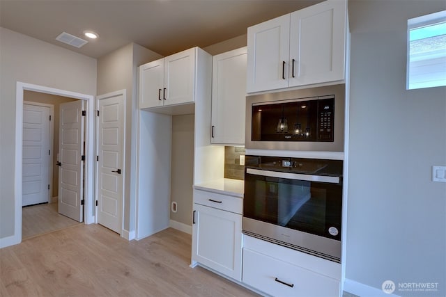 20907 150th St E Unit 1460, Bonney Lake, WA 98391 - kitchen with decorative backsplash, stainless steel oven, built in microwave, light wood-type flooring, and white cabinetry