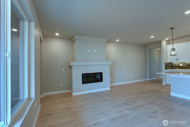 20907 150th St E Unit 1460, Bonney Lake, WA 98391 - unfurnished living room featuring recessed lighting, light wood-style flooring, baseboards, and a glass covered fireplace