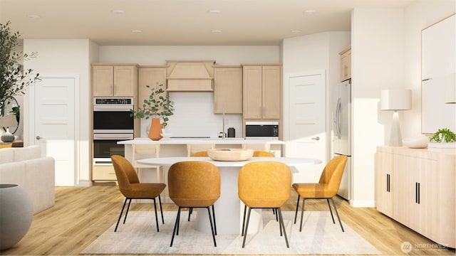 kitchen with double oven, premium range hood, light wood-style floors, an island with sink, and stainless steel fridge