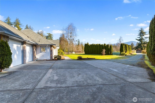 exterior space featuring concrete driveway, a yard, and an attached garage