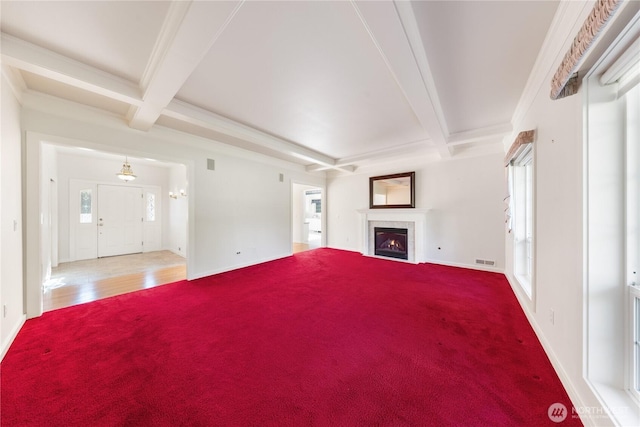 unfurnished living room with a lit fireplace, visible vents, beamed ceiling, and ornamental molding