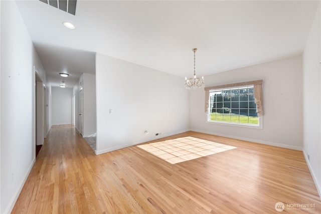 empty room featuring baseboards, light wood-type flooring, visible vents, and an inviting chandelier