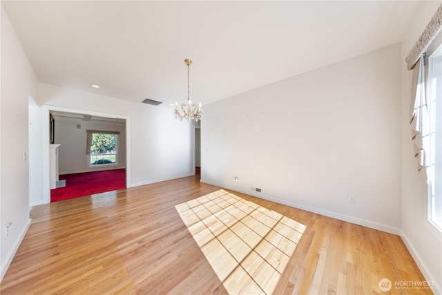 spare room featuring an inviting chandelier, visible vents, baseboards, and light wood finished floors