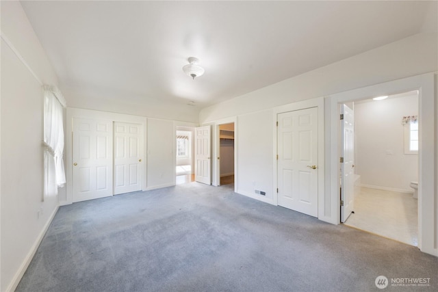 unfurnished bedroom featuring carpet floors, baseboards, and ensuite bathroom