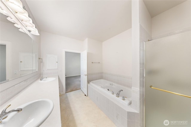 bathroom featuring a stall shower, a garden tub, a sink, and double vanity