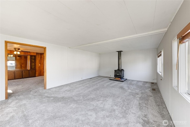 unfurnished living room featuring carpet and a wood stove