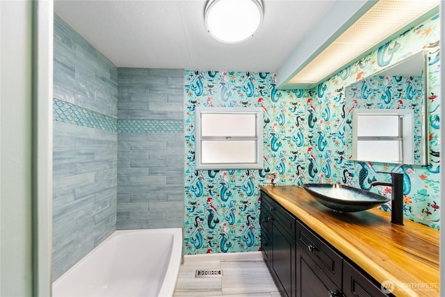 bathroom featuring shower / bathing tub combination, vanity, and wallpapered walls