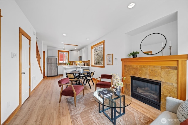 living room featuring recessed lighting, light wood-type flooring, and a tile fireplace