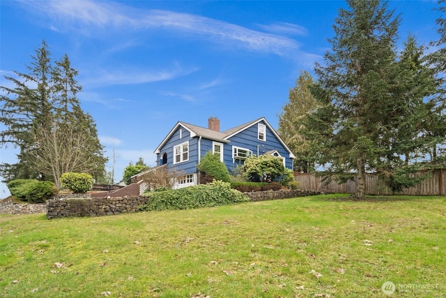 view of property exterior with fence, a chimney, and a lawn